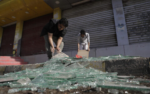 Yemenis clean debris in front of their shops after a US airstrikes in Sanaa, Yemen, Sunday, March 16, 2025. (AP Photo/Osamah Abdulrahman)