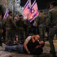 Two demonstrators lie down on the ground as Israeli police officers disperse others blocking a road leading to the Israeli parliament during an anti-government protest after a key vote on the state budget in Jerusalem, March 25, 2025. (AP Photo/Ohad Zwigenberg)