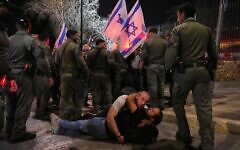 Two demonstrators lie down on the ground as Israeli police officers disperse others blocking a road leading to the Israeli parliament during an anti-government protest after a key vote on the state budget in Jerusalem, March 25, 2025. (AP Photo/Ohad Zwigenberg)