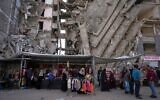 Palestinians buy clothes in a shop next to a destroyed apartment building in preparation for Eid al-Fitr celebrations at Al-Rimal neighborhood in the center of Gaza City, March 28, 2025. (AP Photo/Jehad Alshrafi)