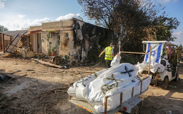 Members of Zaka walk through the destruction caused by Hamas terrorists in Kibbutz Kfar Aza, as they collect the dead bodies, near the Israeli-Gaza border, in southern Israel, October 15, 2023. (Edi Israel/ Flash90)