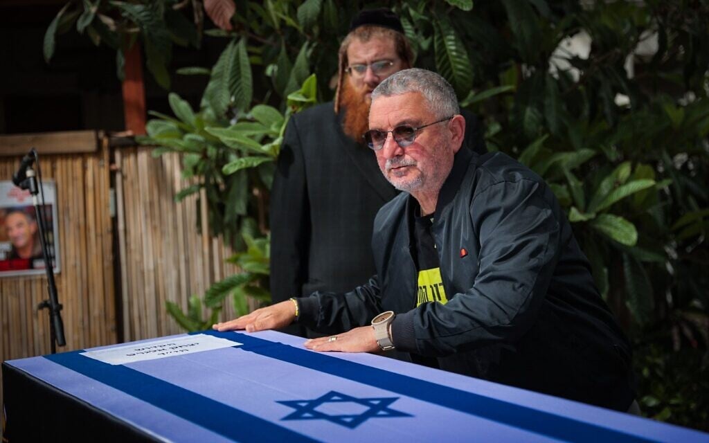 Dani Elgarat standing next to the coffin of his brother, Itzik Elgarat, during a funeral service outside the slain captive's home in Kibbutz Nir Oz, March 3, 2025 (Yossi Aloni/Flash90)