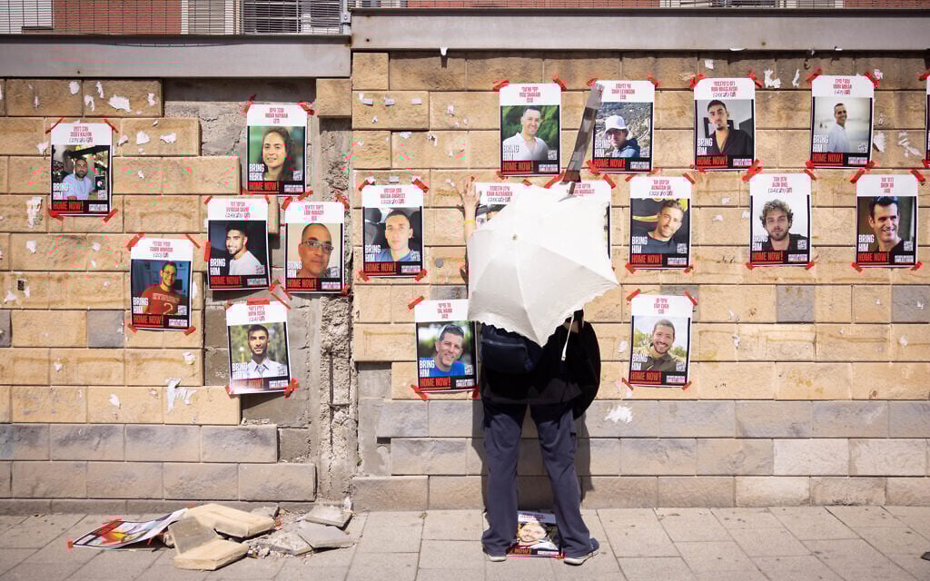 A person looks at posters in Tel Aviv showing Israelis held hostage in Gaza, on March 9, 2025. (Miriam Alster/FLASH90)