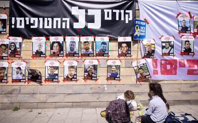 Posters of Israelis held hostage in Gaza are seen posted outside the Defense Ministry in Tel Aviv, under a banner reading: "First, the hostages!" on March 9, 2025. (Miriam Alster/FLASH90)