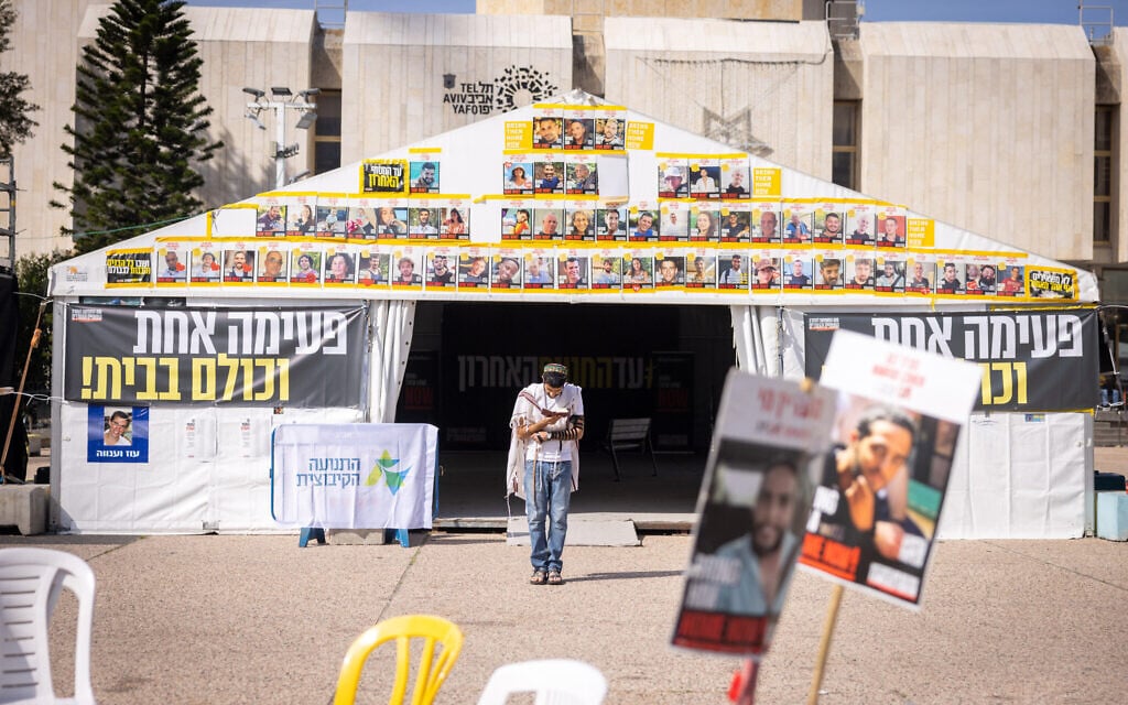 A man prays in front of posters of the Gaza hostages, in Tel Aviv's Hostages Square, March 17, 2025. (Miriam Alster/Flash90)