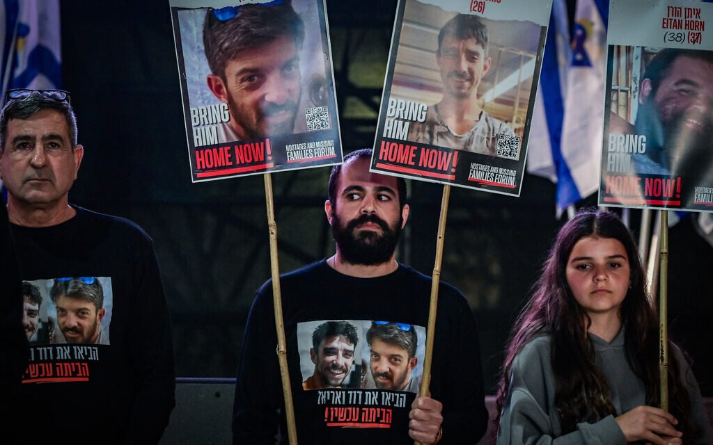 Former hostage Yarden Bibas, center, holds posters calling for the release of David and Ariel Cunio, at Hostage Square in Tel Aviv, March 18, 2025. (Avshalom Sassoni/Flash90)