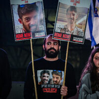 Former hostage Yarden Bibas, center, holds posters calling for the release of David and Ariel Cunio, at Hostage Square in Tel Aviv, March 18, 2025. (Avshalom Sassoni/Flash90)
