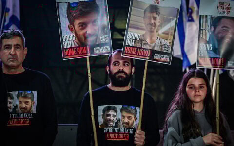 Former hostage Yarden Bibas, center, holds posters calling for the release of David and Ariel Cunio, at Hostage Square in Tel Aviv, March 18, 2025. (Avshalom Sassoni/Flash90)