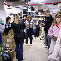 Israelis take cover in a supermarket basement as siren alerts are sounded in Tel Aviv, March 20, 2025. (Miriam Alster/Flash90)