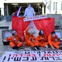 Activists hold a sign reading, 'Qatargate, corruption, treason, recusal now,' in protest against Prime Minister Benjamin Netanyahu, outside the Tel Aviv District Court where his criminal trial is taking place, March 24, 2025. (Tomer Neuberg/ Flash90)