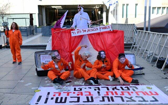 Activists hold a sign reading, "Qatargate, corruption, treason, recusal now" in protest against Prime Minister Benjamin Netanyahu outside the Tel Aviv District Court where his criminal trial is taking place, March 24, 2025. (Tomer Neuberg/Flash90)