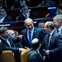 Prime Minister Benjamin Netanyahu speaks with fellow MKs in the Knesset plenum as the 2025 state budget is approved, March 25, 2025. (Yonatan Sindel/Flash90)