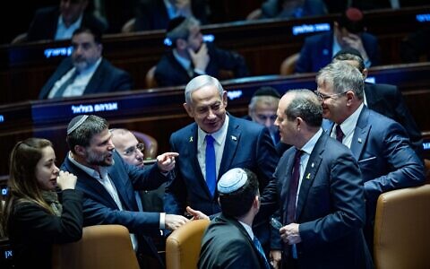 Prime Minister Benjamin Netanyahu speaks with fellow MKs in the Knesset plenum as the 2025 state budget is approved, March 25, 2025. (Yonatan Sindel/Flash90)