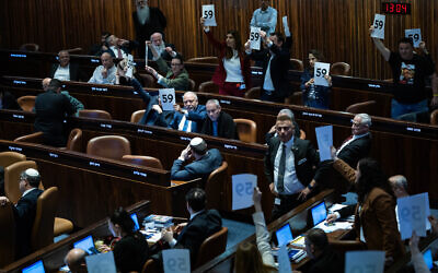 Opposition MKs hold placards highlighting the 59 hostages held by Hamas in Gaza, as the 2025 state budget law is passed by the Knesset, March 25, 2025. (Yonatan Sindel/Flash90)