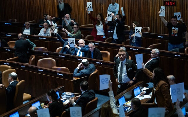 Opposition MKs hold placards highlighting the 59 hostages held by Hamas in Gaza, as the 2025 state budget law is passed by the Knesset, March 25, 2025. (Yonatan Sindel/Flash90)