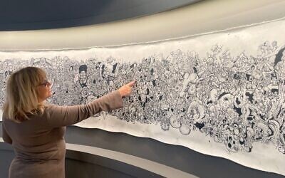 Bible Lands Museum director Risa Levitt shows 'Kuma,' the illustrated scroll made by Eitan Rosenzweig, a soldier killed on November 22, 2023, in battle in Gaza, currently on exhibit in the Jerusalem museum through Summer 2025 (Jessica Steinberg/Times of Israel)