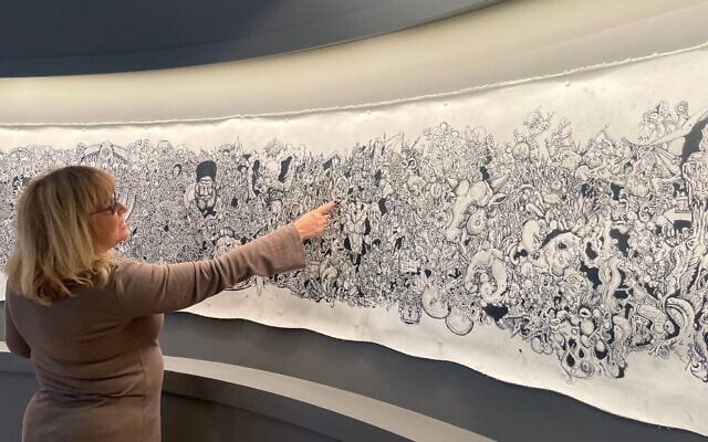 Bible Lands Museum director Risa Levitt shows 'Kuma,' the illustrated scroll made by Eitan Rosenzweig, a soldier killed on November 22, 2023, in battle in Gaza, currently on exhibit in the Jerusalem museum through Summer 2025 (Jessica Steinberg/Times of Israel)