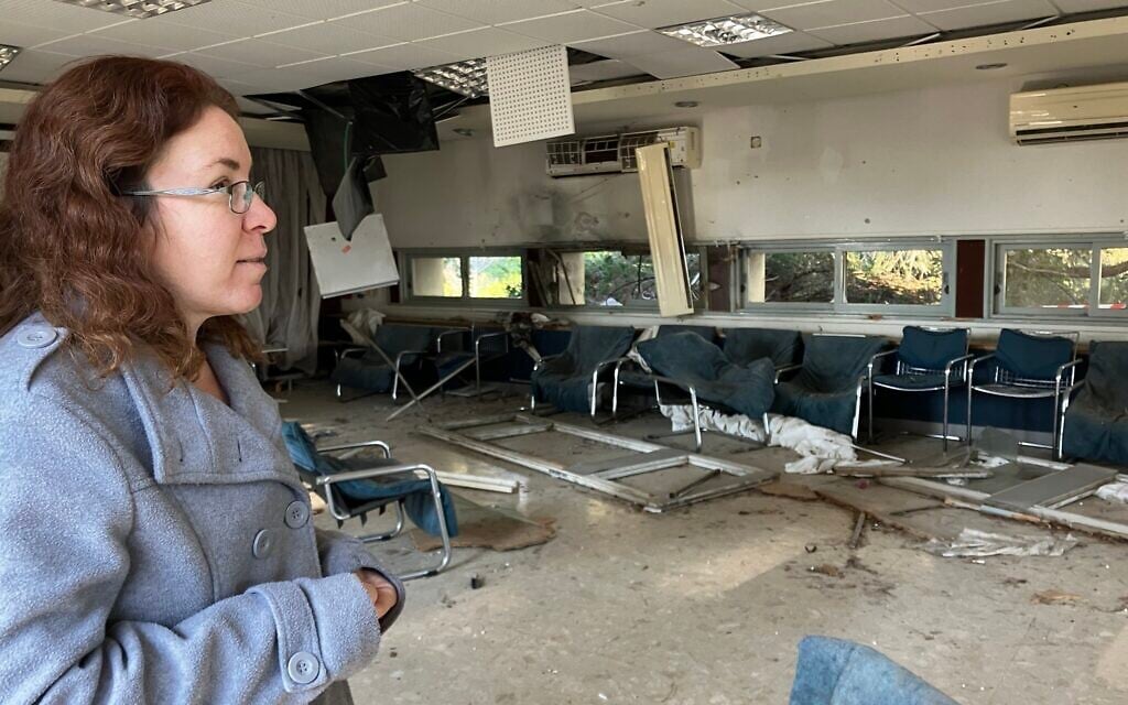 Efrat Amir, a resident of Kibbutz Adamit, surveys the damage from Hezbollah rockets to the kibbutz community center on March 2, 2025. (Diana Bletter/Times of Israel)