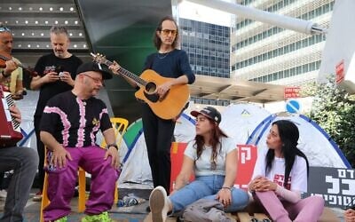 Singer Kobi Oz and the Teapacks band perform for Einav Zangauker and Ilana Gritzewsky, mother and girlfriend of  hostage Matan Zangauker, on March 13, 2025, at the hostage tent encampment on Tel Aviv's Begin Road outside the Defense Ministry (Amir Yaacobi)