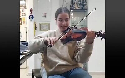Freed hostage Agam Berger plays a violin that once belonged to a Jewish musician who was murdered in the Holocaust, March 8, 2025. (Screen capture: Ynet, used in accordance with Clause 27a of the Copyright Law)