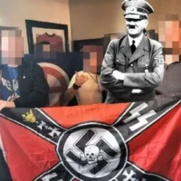 Members of the racist British Movement unfurl a flag with a swastika and SS imagery at the Duke of Edinburgh pub (who say they weren't aware) in Royton, England on April 20, 2025, in celebration of Adolf Hitler's birthday. An image of Hitler has been superimposed onto the image. (British Movement)