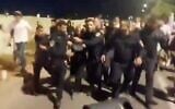Police escort a woman away from right-wing rioters who disrupted a screening at Ra'anana's Beit Samueli synagogue of the joint Israeli-Palestinian Memorial Day ceremony, April 29, 2025. (X screenshot)