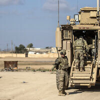 US soldiers step into an armored personnel carrier as they patrol an area in the town of Tal Hamis, southeast of the city of Qameshli in Syria's northeastern Hasakeh governorate, on January 24, 2024. (Delil Souleiman/AFP)