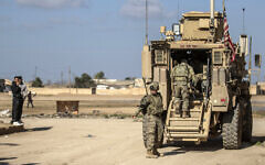 US soldiers step into an armored personnel carrier as they patrol an area in the town of Tal Hamis, southeast of the city of Qameshli in Syria's northeastern Hasakeh governorate, on January 24, 2024. (Delil Souleiman/AFP)
