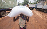 A woman carries a bag of food aid distributed by the World Food Program (WFP) to displaced people from the province of Cabo Delgado, in the town of Namapa, Erati district of Nampula, Mozambique on February 27, 2024. (Alfredo Zuniga / AFP)