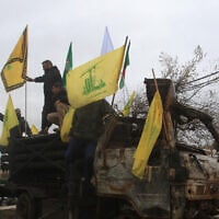 People pose for a picture on a burnt Hezbollah rocket launcher in the southern Lebanese village of Kfar Tibnit on November 27, 2024, after a ceasefire between Israel and Hezbollah took effect. (Mahmoud Zayat/AFP)