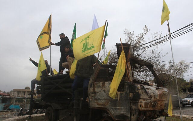 People pose for a picture on a burnt Hezbollah rocket launcher in the southern Lebanese village of Kfar Tibnit on November 27, 2024, after a ceasefire between Israel and Hezbollah took effect. (Mahmoud Zayat/AFP)
