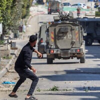 Illustrative: Palestinians hurl stones at Israeli forces during a raid in the West Bank's Balata refugee camp, east of Nablus, March 24, 2025. (Zain Jaafar / AFP)