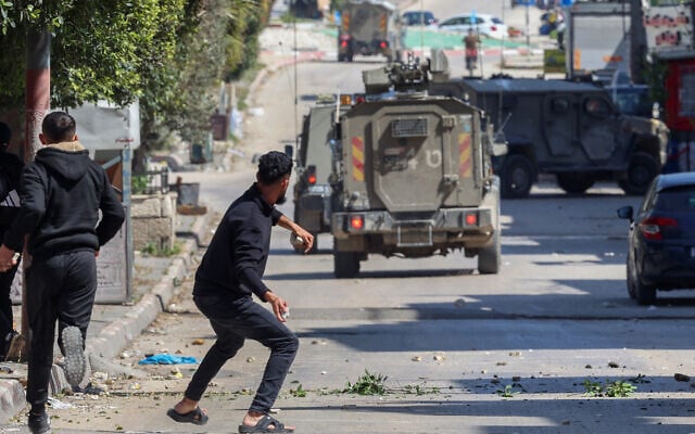 Illustrative: Palestinians hurl stones at Israeli forces during a raid in the West Bank's Balata refugee camp, east of Nablus, March 24, 2025. (Zain Jaafar / AFP)