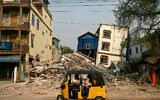 A three-wheeled motorcycle drives past collapsed and damaged buildings in Mandalay, after the March 28 earthquake struck central Myanmar, April 3, 2025. (AFP/ Sai Aung MAIN)