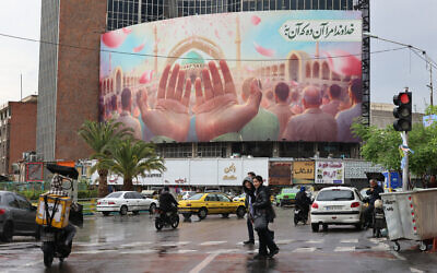 Illustrative: Iranians cross a road on a rainy day in Tehran on April 5, 2025. (ATTA KENARE/AFP)