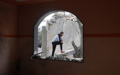 A Palestinian man stands on debris in a heavily damaged building following an overnight Israeli airstrike on Deir al-Balah in the central Gaza Strip on April 7, 2025. (Eyad Baba/AFP)