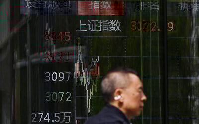 A man walks past a screen showing Chinese stock market movements at a securities company in Beijing on April 8, 2025. (GREG BAKER / AFP)