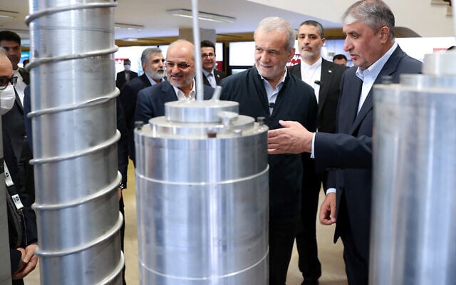 A handout picture provided by the Iranian presidency shows Iran's President Masoud Pezeshkian (2nd R) and the Atomic Energy Organisation of Iran (AEOI) chief Mohammad Eslami (R) during the 'National Day of Nuclear Technology,' in Tehran, on April 9, 2025 (Iranian Presidency / AFP)