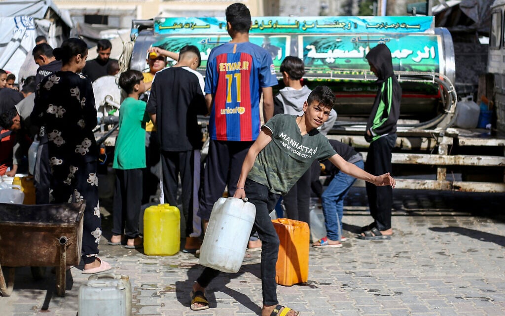 Displaced Palestinians line up to fill their containers with water at the Bureij refugee camp in the central Gaza Strip on April 10, 2025. (Eyad BABA / AFP)