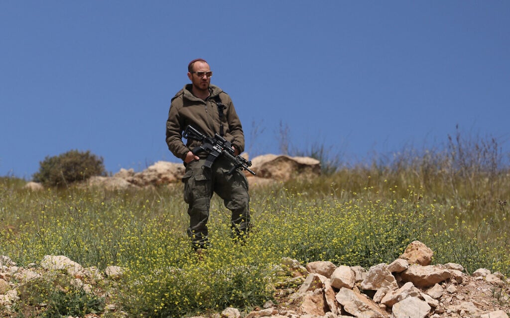 An Israeli soldier watches from a hill after army bulldozers demolished houses belonging to the Al-Hirsh family, in the village of Al-Rihaya, near the West Bank city of Hebron on April 10, 2025. (HAZEM BADER / AFP)