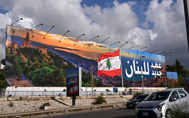 Commuters drive past a newly-installed billboard bearing the image of a Lebanese flag and a statement that reads in Arabic "Lebanon a new era", replacing a Hezbollah billboard, on the road leading to Beirut's Rafic Hariri International airport on April 10, 2025. (Photo by JOSEPH EID / AFP)