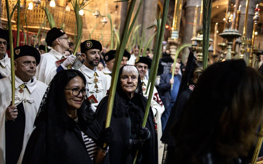 Christian pilgrims walk with palm fronds inside the Church of the Holy Sepulchre on Palm Sunday in Jerusalem on April 13, 2025. (Photo by JOHN WESSELS / AFP)