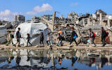 People walk past a puddle of water by a tent shelter erected near the rubble of a collapsed building in the Nasr neighborhood in western Gaza City on April 15, 2025. (Omar AL-QATTAA / AFP)