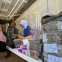 A Syrian woman speaks with an employee at a currency exchange shop in Damascus on April 16, 2025 (Photo by LOUAI BESHARA / AFP)