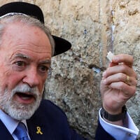 New US Ambassador to Israel Mike Huckabee holds up a note he says was given him by US President Donald Trump to be place in the crevices of the Western Wall, in the Old City of Jerusalem, April 18, 2025. (Gil Cohen-Magen / AFP)