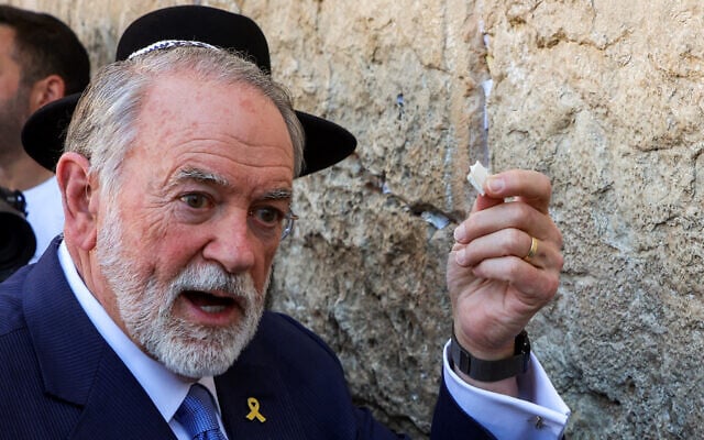 New US Ambassador to Israel Mike Huckabee holds up a note he says was given him by US President Donald Trump to be place in the crevices of the Western Wall, in the Old City of Jerusalem, April 18, 2025. (Gil Cohen-Magen / AFP)