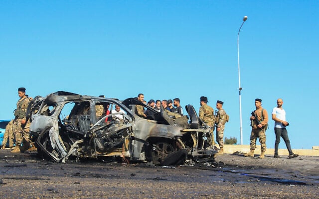 Lebanese soldiers inspect the site near a burnt-out vehicle hit by an Israeli drone strike in Ghazieh, near Sidon, on April 18, 2025. (Mahmoud ZAYYAT / AFP)