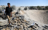 A Palestinian youth walks around a large crater caused by an Israeli strike at a camp for displaced Palestinians in northern Khan Younis in the southern Gaza Strip on April 19, 2025. (AFP)