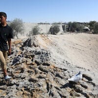A Palestinian youth walks around a large crater caused by an Israeli strike at a camp for displaced Palestinians in northern Khan Younis in the southern Gaza Strip on April 19, 2025. (AFP)