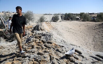 A Palestinian youth walks around a large crater caused by an Israeli strike at a camp for displaced Palestinians in northern Khan Younis in the southern Gaza Strip on April 19, 2025. (AFP)